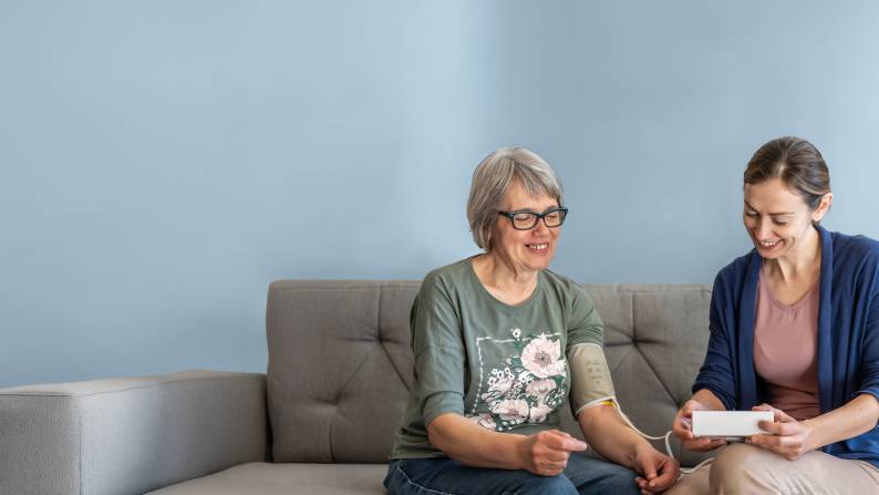 Caregiver providing at-home monitoring test on a senior patient.