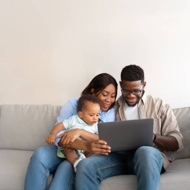 A mom, dad and baby are all looking at a laptop.