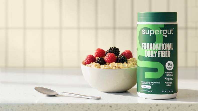 A bowl of oatmeal topped with black and red berries are shown alongside supergut’s foundational daily fiber supplements.