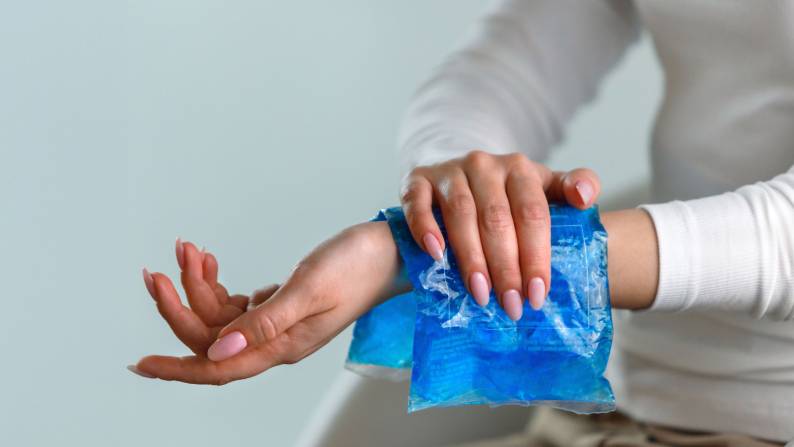 Hand reaching out with an icepack on wrist.