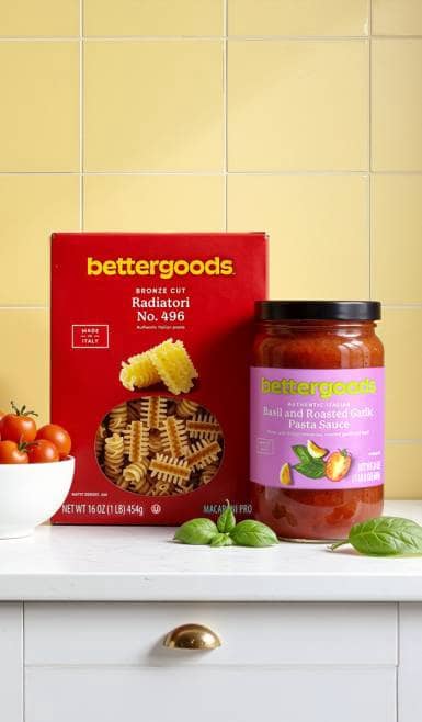 A bowl of cherry tomatoes, a box of bettergoods bronze cut radiatori pasta, and a jar of bettergoods basil and roasted garlic pasta sauce.