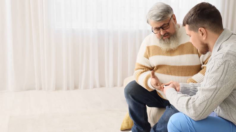 Caregiver assisting senior patient with an at-home diabetes test.