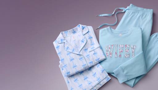 Light blue bridal-themed pajamas with bow prints displayed beside a sweatshirt with the word wifey printed across and matching light blue pants.
